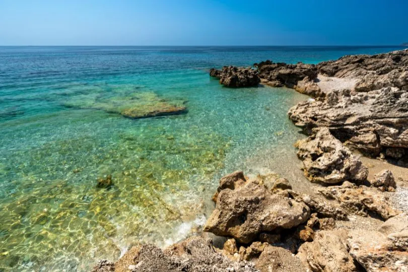 Felsstrand in Albanien mit klarem ruhigem Wasser. 