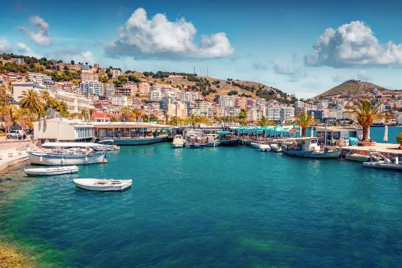 Kleines Dorf namens Sarandë in Albanien vor der Bucht mit kleinen Booten.