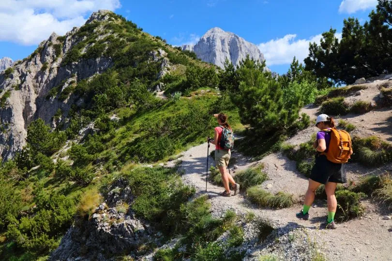 Zwei Frauen wandern auf einem schmalen Pfad durch die Berge Albaniens.