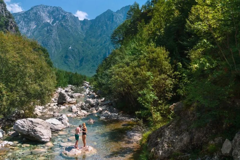 Mutter und ihr Sohn stehen in einem Fluss inmitten der Wälder und Berge in Albanien.