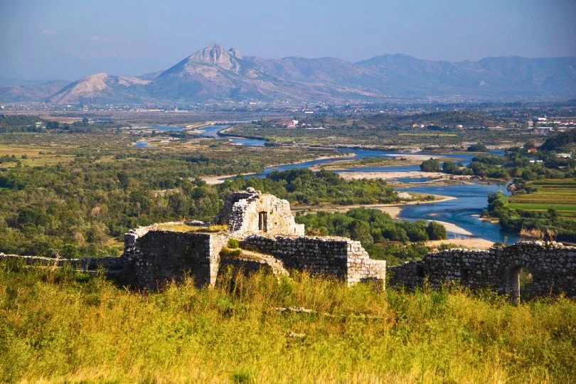 Ruinen in Albanien vor einer vielfältigen Landschaft mit Flüssen und Vegetation.