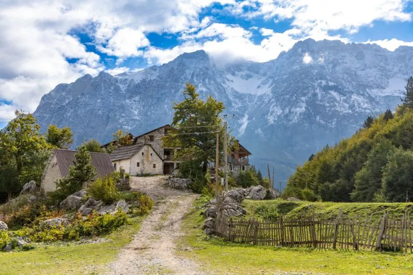 Einige Häuschen in Albanien stehen vor mächtigen, felsigen Bergen.