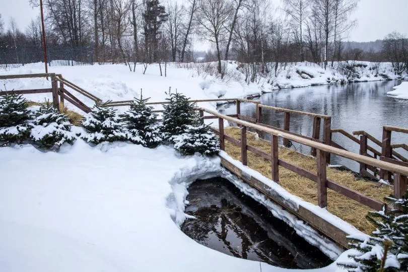 Brücke führt über einen eisiges Fluss. Die Landschaft drum herum ist von Schnee bedeckt.