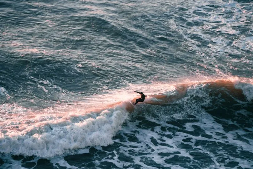 Surfer auf den Wellen am Praia Ribeira d‘Ilhas, einem der schönsten Strände Portugals bei Ericeira.