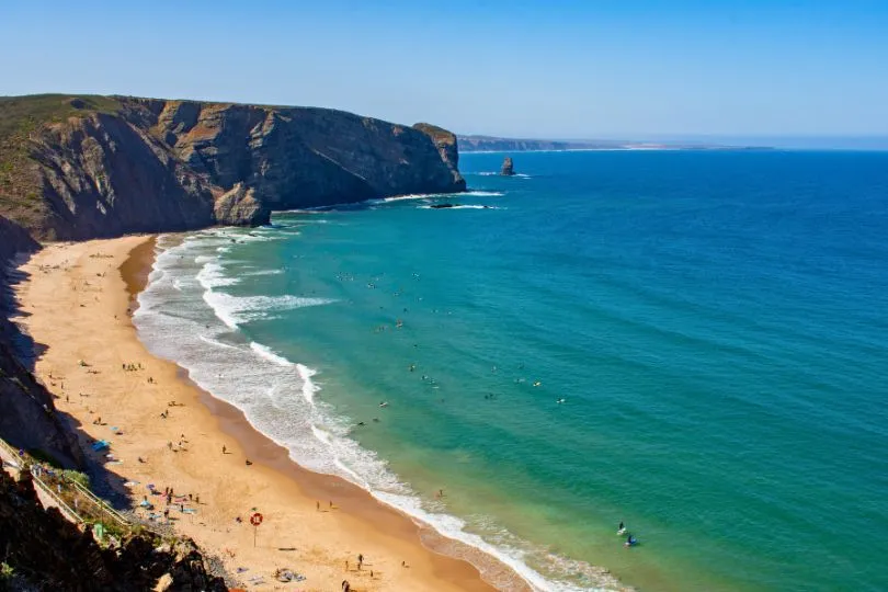 Der lange Sandstrand vor der Klippe an der Praia di Arrifana in Portugal.