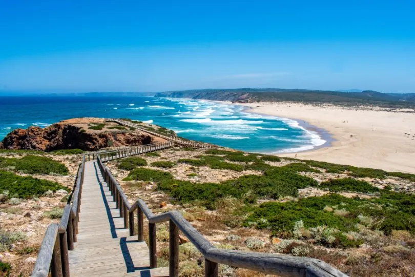 Eine Holztreppe führt runter zum Praia da Bordeira in Portugal.