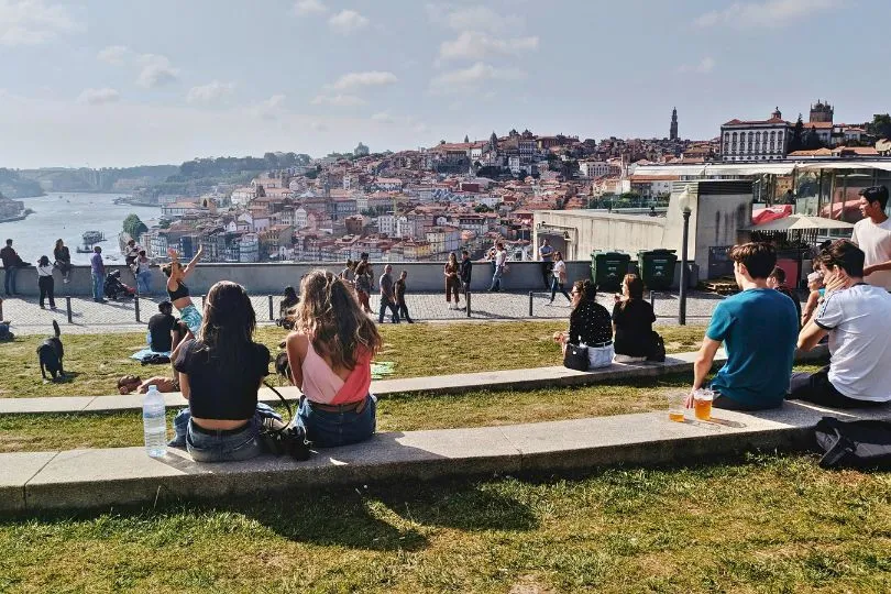 Menschen in Porto sitzen auf einer Terrasse mit Aussicht auf den Rio Douro und Porto.