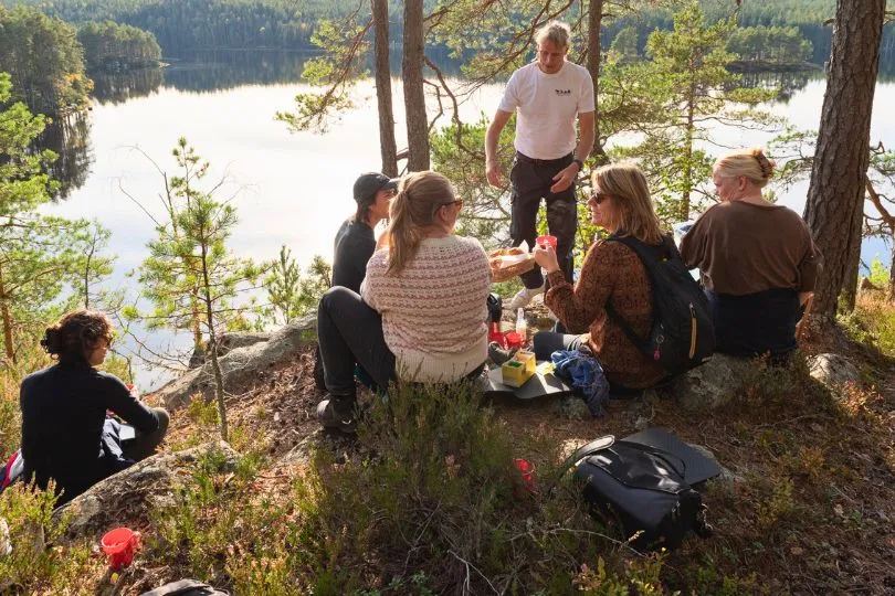 Reisende genießen eine schwedische Fika (Kaffeepause) bei einer Pause am See.