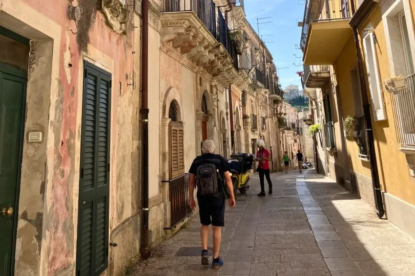 Tourist läuft durch eine gemütliche helle Gasse auf Sizilien.