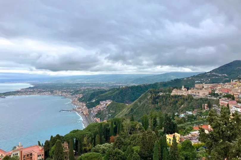 Aussicht auf eine Küstenlinien mit Wäldern und kleinen Dörfern mit roten Dächern auf Sizilien.