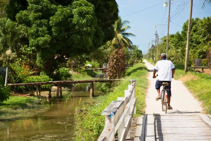 Mann fährt auf seinem Fahrrad an einen Flussweg entlang in Surinam.