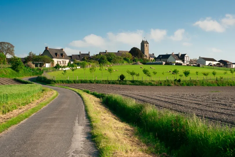 Ländliche Landschaft bei Beauvoir in der Bretagne mit Feldern, Weiden und einem kleinen Dorf.