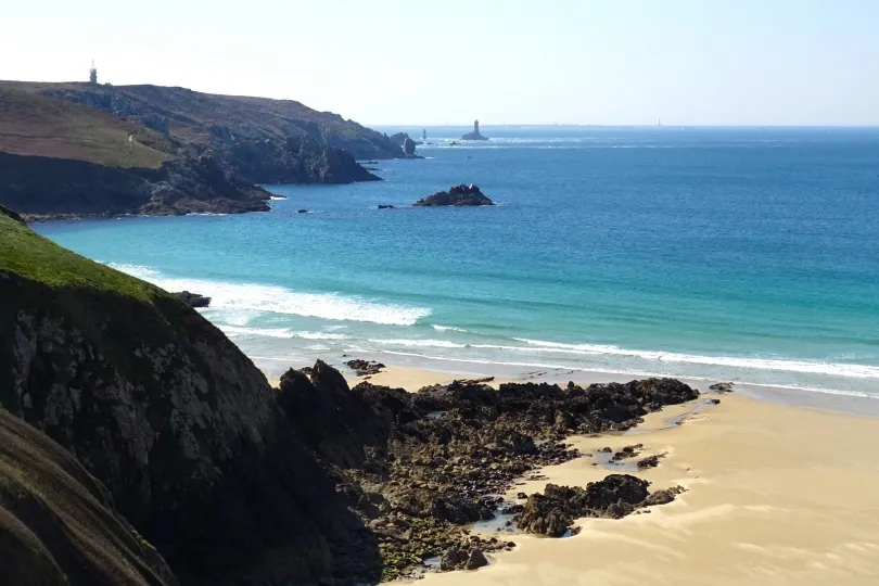 Küstenlandschaft am Cap d’Erquy in der Bretagne mit Sandstrand, türkisblauem Meer und Leuchttürmen im Hintergrund.