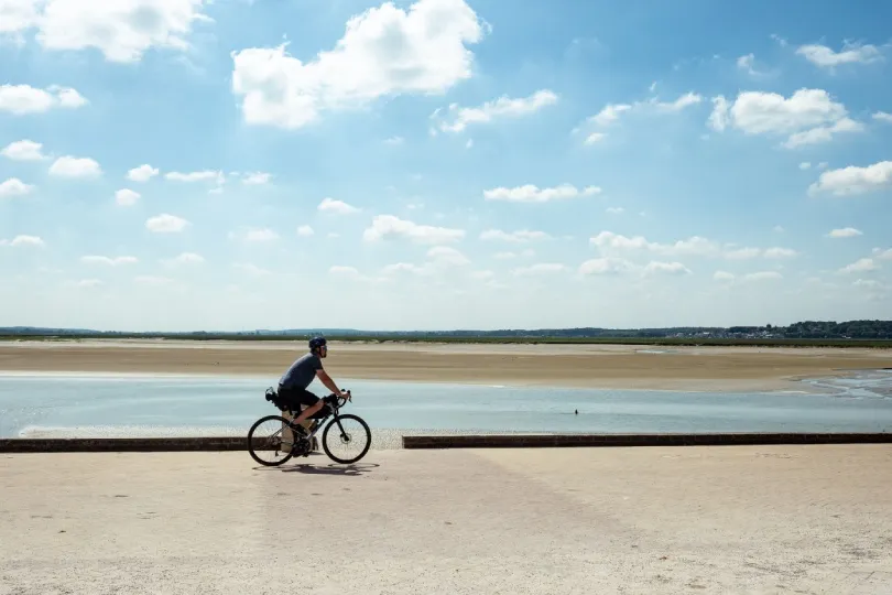 Radfahrer an der französischen Küste mit Blick auf eine weite Bucht und Sandflächen bei Ebbe.