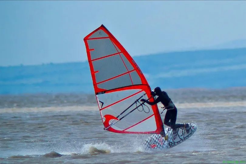 Mann im Neoprenanzug surft im Winter in Schweden.