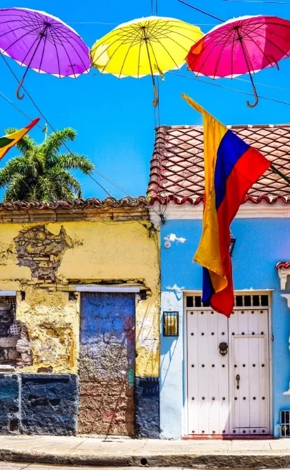 Kolumbianische Flagge, bunte Schirme und Hauswände in Cartagena