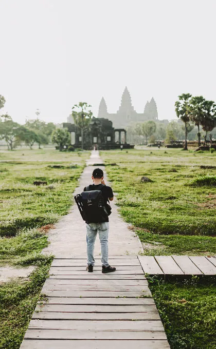 Ein Reisender steht in Kambodscha vor einem Tempel und macht ein Foto