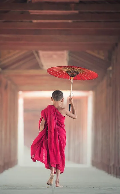 Ein Kind läuft mit einem Sonnenschirm in einem Tempel von Myanmar