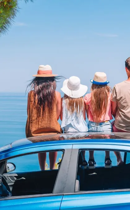 Familie auf Auto bei einer Mietwagenrundreise.