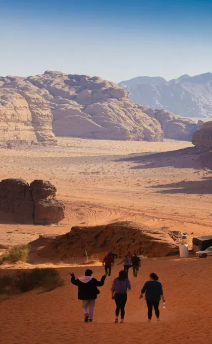 Eine Gruppe Menschen läuft einen Hügel in der jordanischen Wüste hinab.