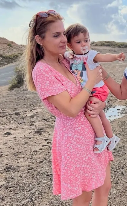 Eine Frau in einem rosa Kleid, die ein Baby hält