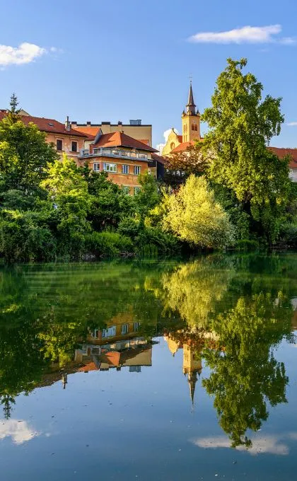 Siedlung und Bäume spiegeln sich im Wasser.