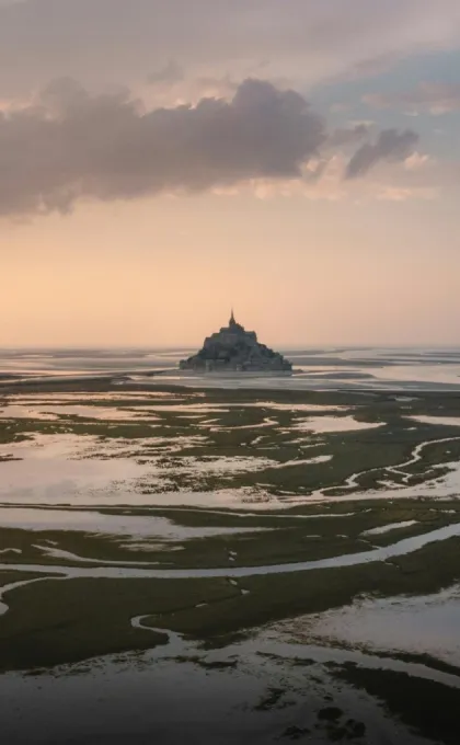 Insel mit Kloster in weiter Wattlandschaft bei Sonnenuntergang.