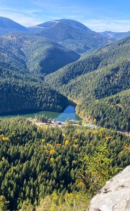 Bergsee inmitten von mit Nadelwäldern überzogenen Bergen.