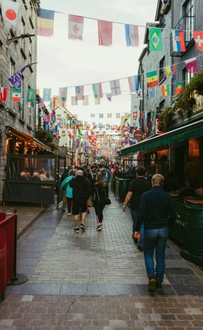 Enge, gut besuchte Gasse in Irland mit Restaurants auf beiden Seiten und bunten Girlanden mit Länderflaggen.