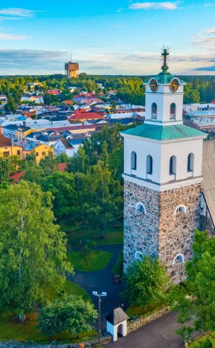 Kirche in Rauma im Vordergrund, das Dort mit viel Grün im Hintergrund.