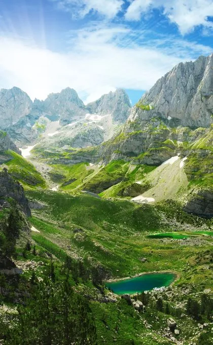 Berglandschaft in Albanien mit grünen Tälern, rauen Felsen und einem Bergsee.