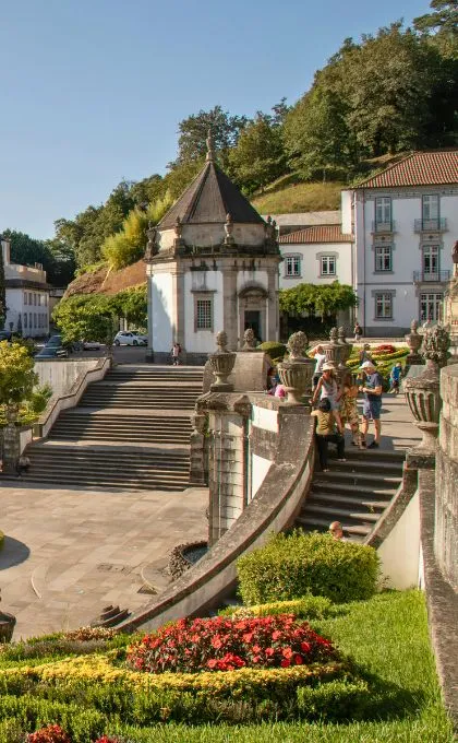 Touristen stehen in einem Park vor einem historischen Gebäude in Portugal.