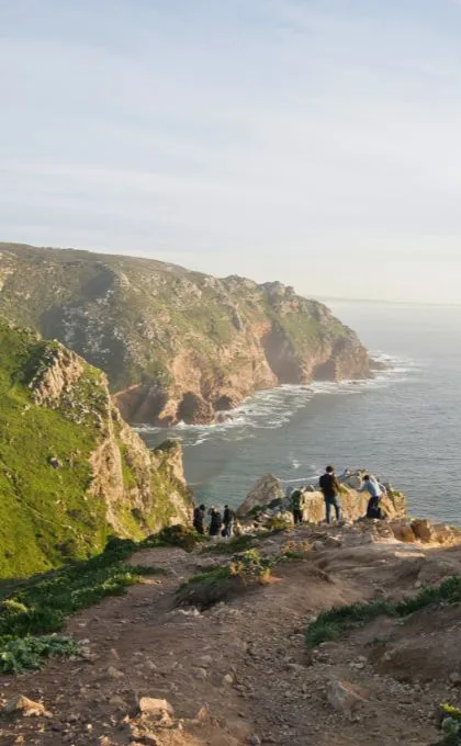 Reisende stehen vor einer Klippe in Portugal am Meer.