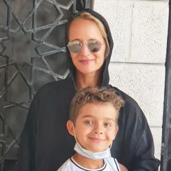 Nina steht mit ihrem SohnAnas vor einer Hauswand in Jordanien