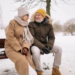 Ein Pärchen sitzt auf einer Bank im Winterurlaub Slowenien