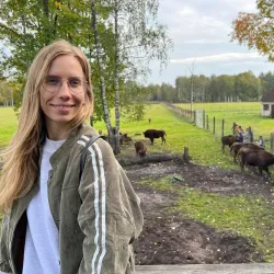 Reiseexpertin Baltischen Staaten. Sie besucht eine Farm mit ein paar Kühe im Hintergrund.