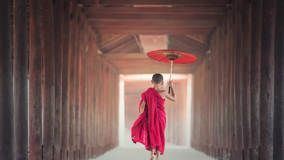 Was muss man sehen in Myanmar? Ein Kind läuft mit einem Sonnenschirm durch einen Tempel