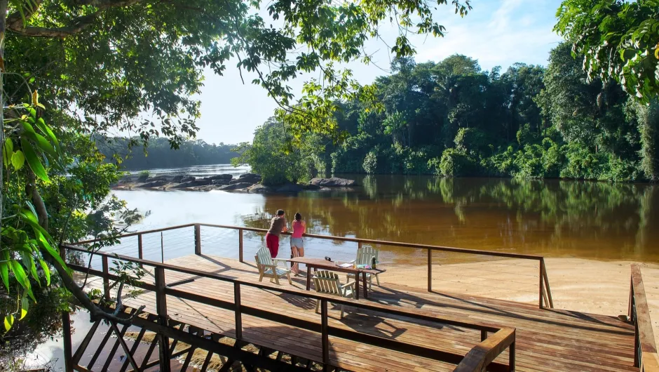 Zwei Reisende stehen in Suriname auf einer Terrasse am Fluss