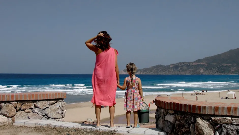 Eine Mutter steht mit ihrem Kind am Strand in Sardinien