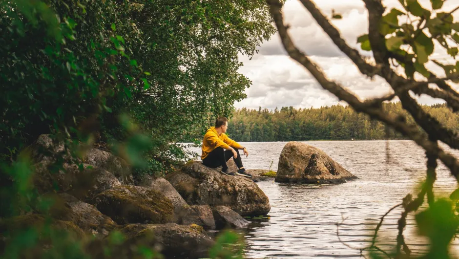 Ein Mann sitzt auf einem Stein während seiner Finnland Reise