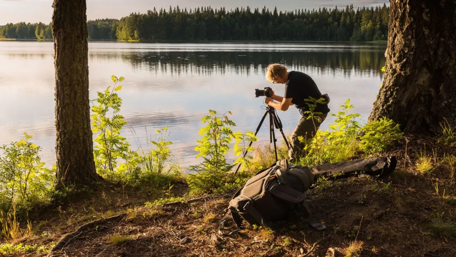 Eine Person steht während der Schweden Reise am See und fotografiert