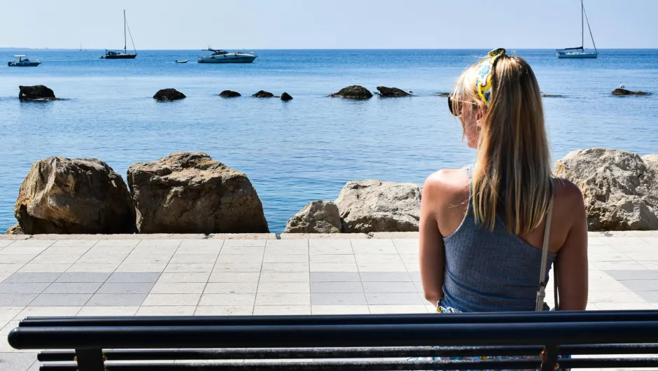 Frau sitzt auf Bank am Wasser in Italien.