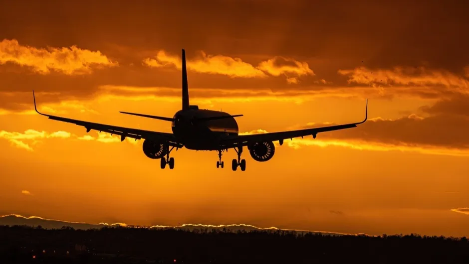 ein Flugzeug im Flug vor einem Sonnenuntergangshimmel.