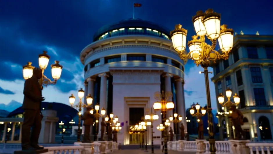 Gebäude mit Kuppeldach und Säulen am Eingang, beleuchtet von Straßenlaternen.