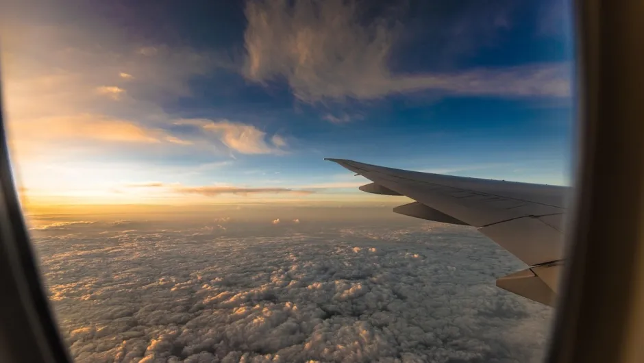 Fensterplatz im Flugzeug zeigt Wolken und sonnenuntergang .