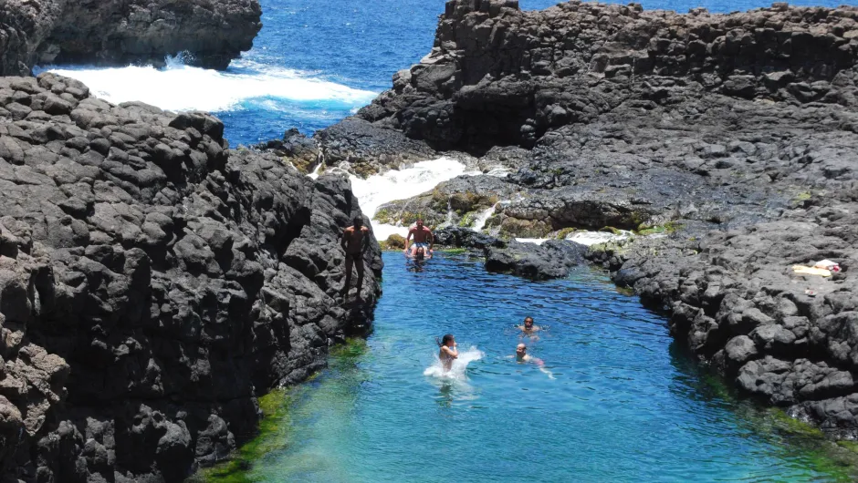 natürliches Schwimmbecken, das von dunklen vulkanischen Felsen umgeben ist.