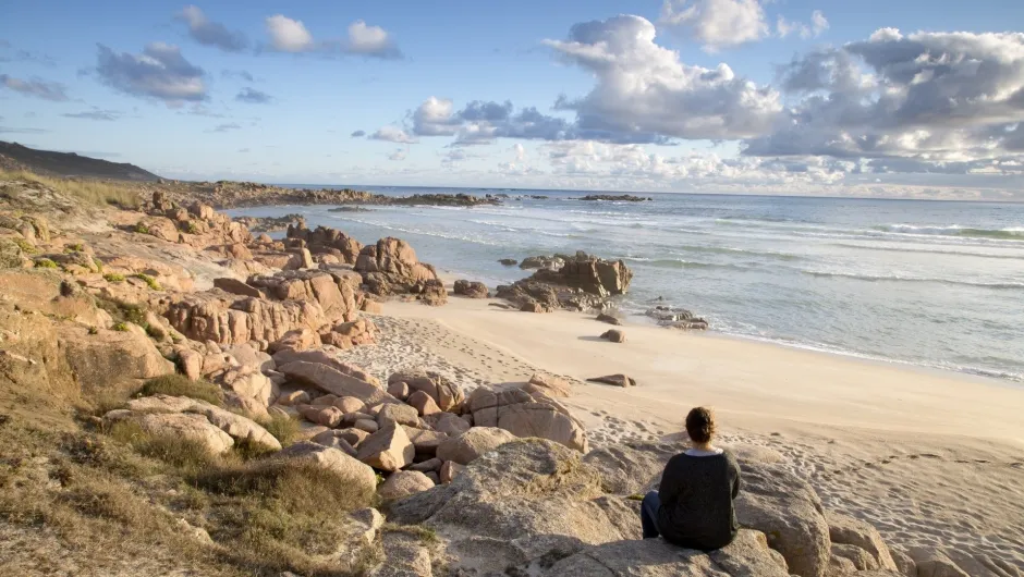 Ein Person sitzt am Strand.