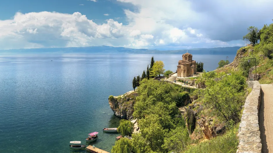 Blick auf einen See in Albanien mit grüner Steilküste im Vordergrund.