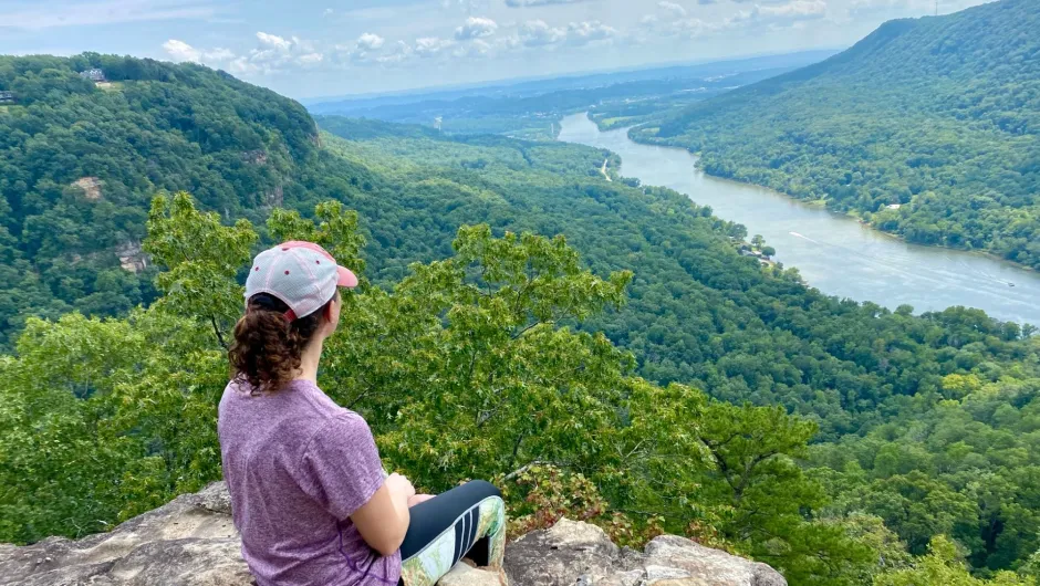 Frau von hinten die über ein grünes Tal blickt.