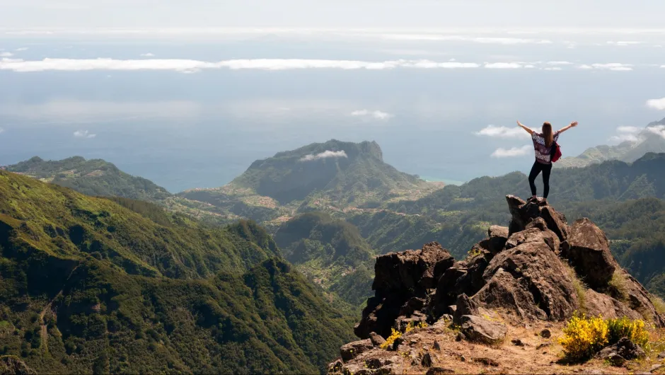Madeira Rundreisen: Eine unabhängige Wanderin genießt den Ausblick vom Gipfel während einer Naturwanderung durch die beeindruckende Bergwelt Madeiras.
